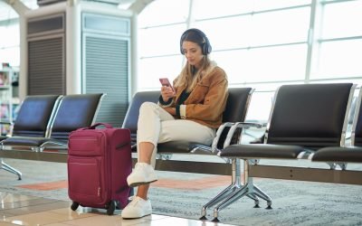 Headphones, music phone and woman in airport lobby on social media, internet browsing or web scrolling. Travel flight, mobile technology and female with smartphone app for streaming radio or podcast