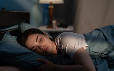 Young sad woman lying in bed late at night trying to sleep suffering insomnia. Girl in bed scared on nightmares looking worried and stressed. Sleeping disorder and insomnia concept